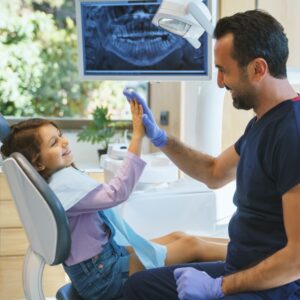 dentist high fives child in dental chair